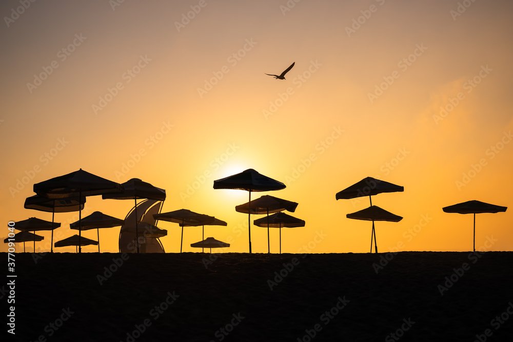Sunrise with sunshade and life guard station silhouette