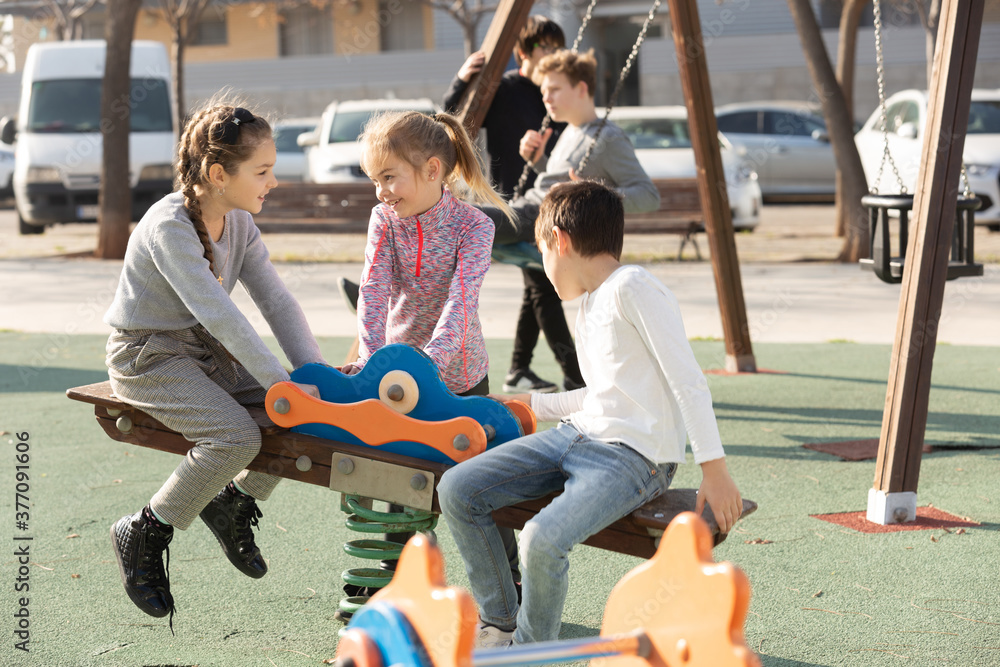 Company of kids are teetering on the swing on the playground. High quality photo