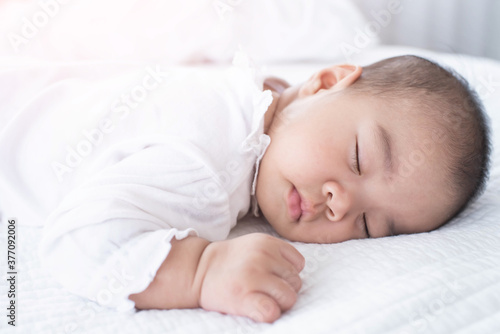 portrait of a beautiful sleeping baby on white. Cute little baby sleeping on bed at home.