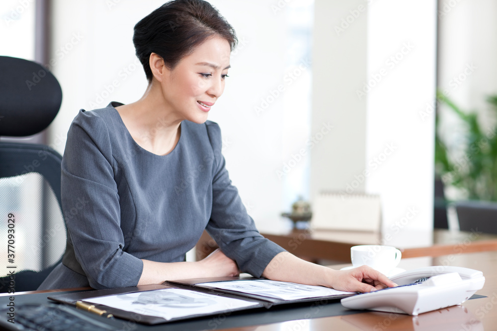 Businesswoman dialing telephone in office Businesswoman dialing telephone in office