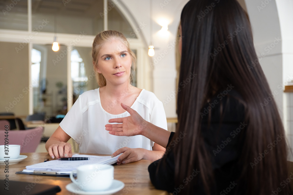 Successful young business ladies meeting at co-working for signing agreement, woman offering hand for handshake. Medium shot. Cooperation concept Successful young business ladies meeting at co-working for signing agreement, woman offering hand for handshake. Medium shot. Cooperation concept
