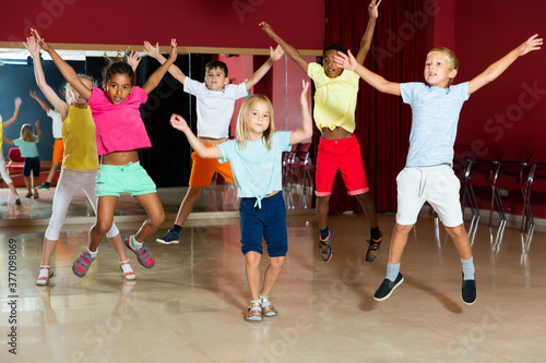 Smiling children jumping while studying modern style dance in class indoors