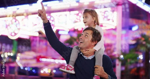 Authentic shot of a happy smiling family is having fun together in amusement park with luna park lights at night. photo