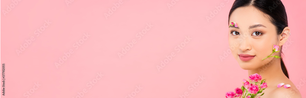 webside header of young asian woman with buds and petals on face and shoulder, near tiny roses isolated on pink webside header of young asian woman with buds and petals on face and shoulder, near tiny roses isolated on pink