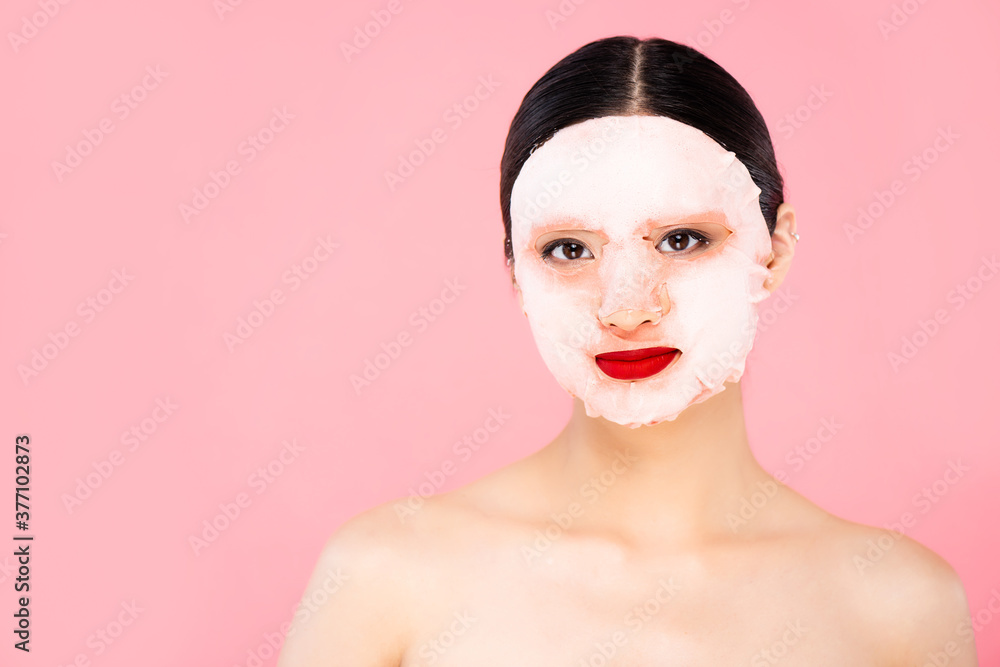 nude asian woman in face mask looking at camera isolated on pink nude asian woman in face mask looking at camera isolated on pink