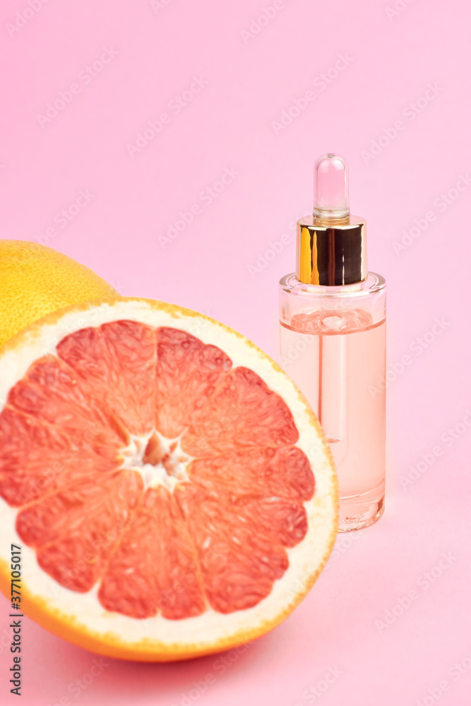 Essential citrus oil in glass bottle with fresh grapefruits. Essential citrus oil in glass bottle with fresh grapefruits.