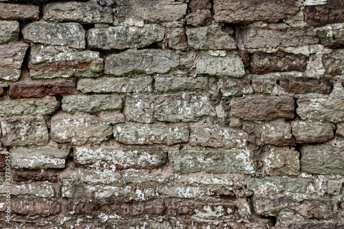 The surface of an old stone wall, masonry of uneven wild hewn stones.