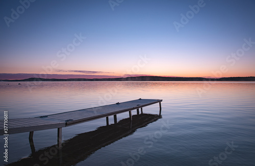 Small boat pier in cottage country. Calm lake with clear sky.