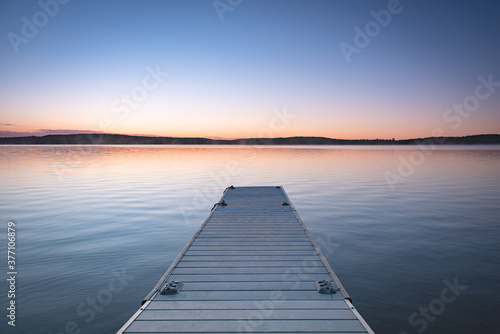 Fototapeta Naklejka Na Ścianę i Meble -  Small boat pier in cottage country. Calm lake with clear sky.