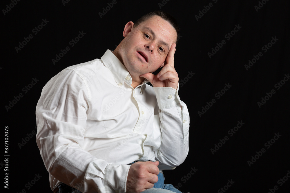 adult man with down syndrome poses in photo studio with white shirt and jeans adult man with down syndrome poses in photo studio with white shirt and jeans