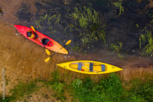 multicolored empty kayaks on the river bank, view from above
