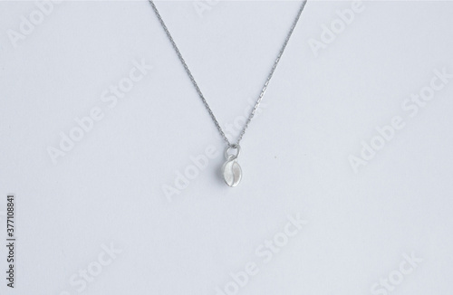 pendant made of silver in the form of a coffee bean on a thin chain on a white background. Jewelry, pendant for coffee lovers. Memorable gift, relationship, love. Coffee day