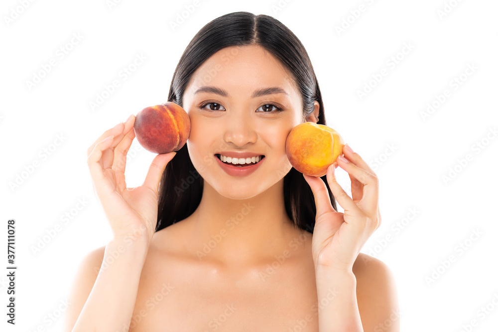 nude asian woman holding ripe peaches near face while looking at camera isolated on white nude asian woman holding ripe peaches near face while looking at camera isolated on white