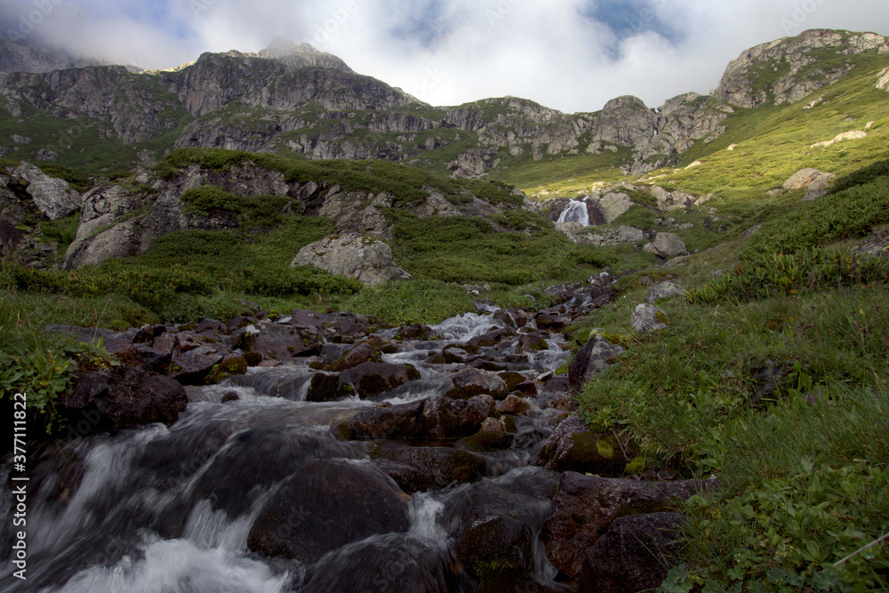 Alpine stream with waterfalls.
Alpine stream among rocks overgrown with green bushes. Hanging valley of the Koshtansu river. Caucasus. Alpine stream with waterfalls.
Alpine stream among rocks overgrown with green bushes. Hanging valley of the Koshtansu river. Caucasus.