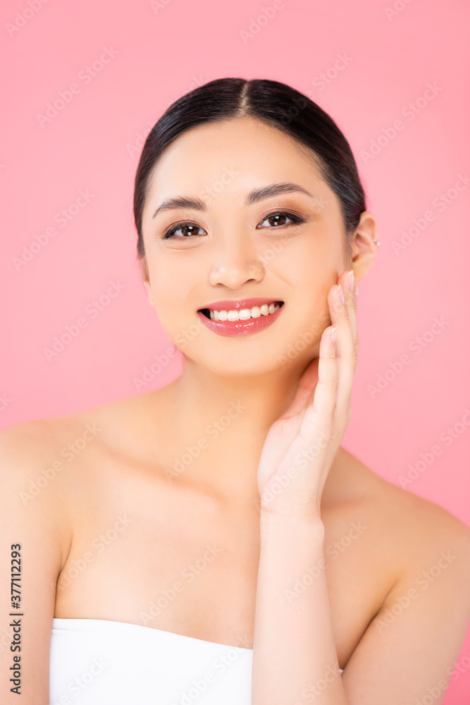 young asian woman touching face and looking at camera isolated on pink young asian woman touching face and looking at camera isolated on pink