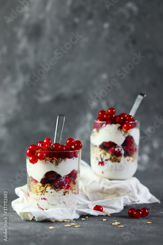 Granola Parfait with Yogurt, oat granola, fresh berries in glass , copy space for text recipe on gray background.