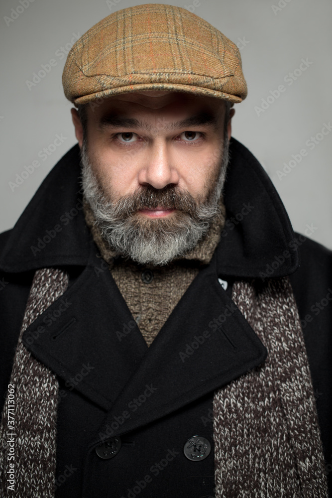 Close up portrait of 50-year-old man wearing coat and hat. Copy-space. Studio shot Close up portrait of 50-year-old man wearing coat and hat. Copy-space. Studio shot