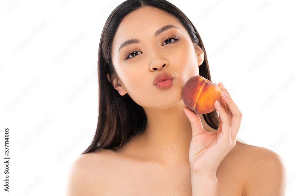 naked asian woman pouting lips while holding ripe peach near face isolated on white naked asian woman pouting lips while holding ripe peach near face isolated on white
