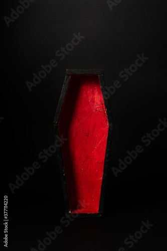 Miniature open black-red coffin on a black background. Festive halloween concept. A place for your product.