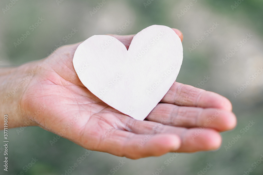 Grandma's hand holds a heart. The concept of protecting the elderly, retirement