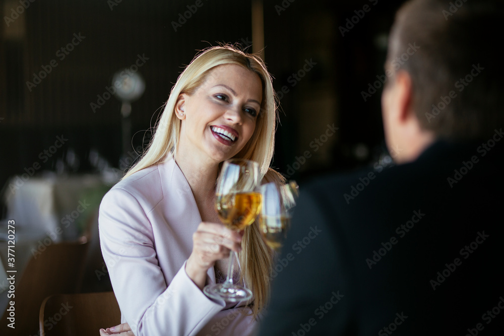 Beautiful businesswoman dressed in the suit drinking wine. Businessman and businesswoman enjoying in the restaurant.. Beautiful businesswoman dressed in the suit drinking wine. Businessman and businesswoman enjoying in the restaurant..