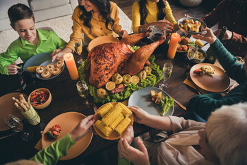 Cropped photo of full family relative gathering sit served dinner table share mom granny fetch food plate corn potato snacks lovely atmosphere multi generation in evening living room indoors