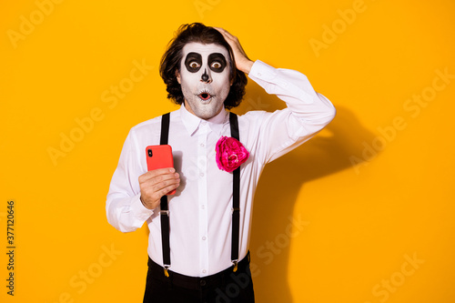 Portrait of his he nice handsome spooky wondered stunned astonished amazed guy using device fake news calavera blog post comment reaction isolated bright vivid shine vibrant yellow color background