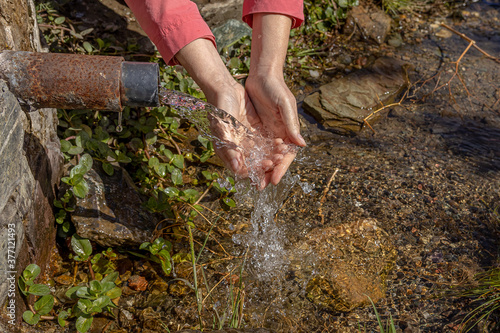 a girl washes her hands under a stream of spring water. close up