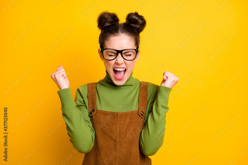 Photo of funny youngster student lady two buns raise fists celebrate excellent best result passing examination wear specs green pullover brown overall dress isolated yellow color background Photo of funny youngster student lady two buns raise fists celebrate excellent best result passing examination wear specs green pullover brown overall dress isolated yellow color background