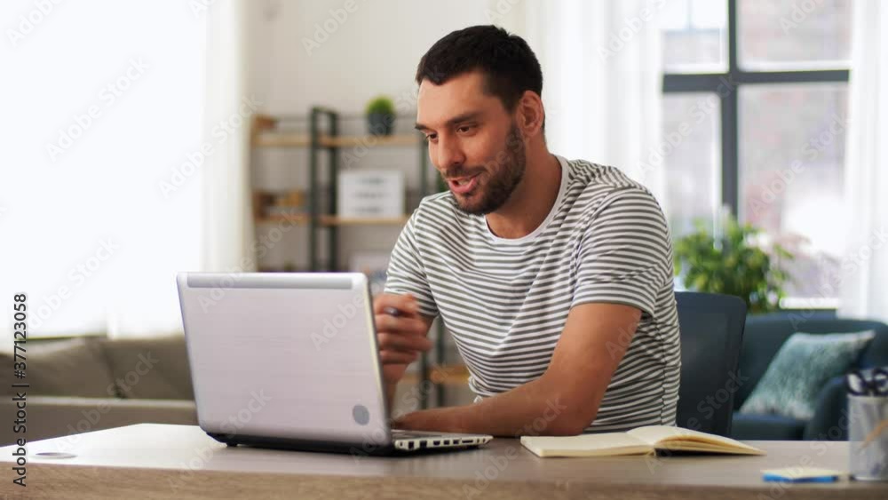 technology, remote job and lifestyle concept - happy smiling man with laptop computer having video call and waving hand at home office technology, remote job and lifestyle concept - happy smiling man with laptop computer having video call and waving hand at home office