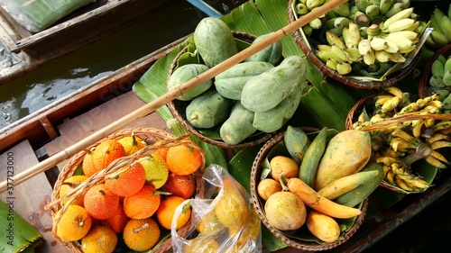 Iconic asian Lat Mayom floating market. Khlong river canal, long-tail boat with tropical exotic colorful fruits, organic locally grown vegetables. Top view of harvest and street food in wooden canoe photo