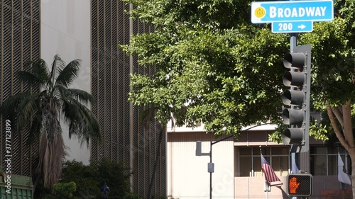 Broadway street name, odonym sign and traffic light on pillar in USA. Road intersection in downtown of city. Crossroad in urban central business district. Nameplate banner with title of main avenue