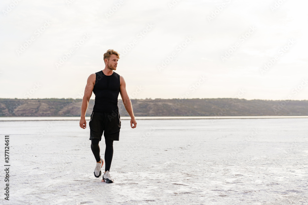 Image of caucasian athletic sportsman walking while working out Image of caucasian athletic sportsman walking while working out