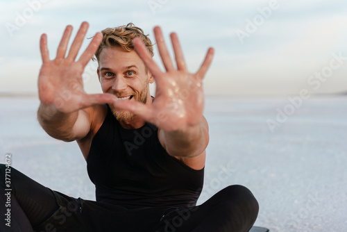 Image of joyful sportsman doing showing his palms while working out