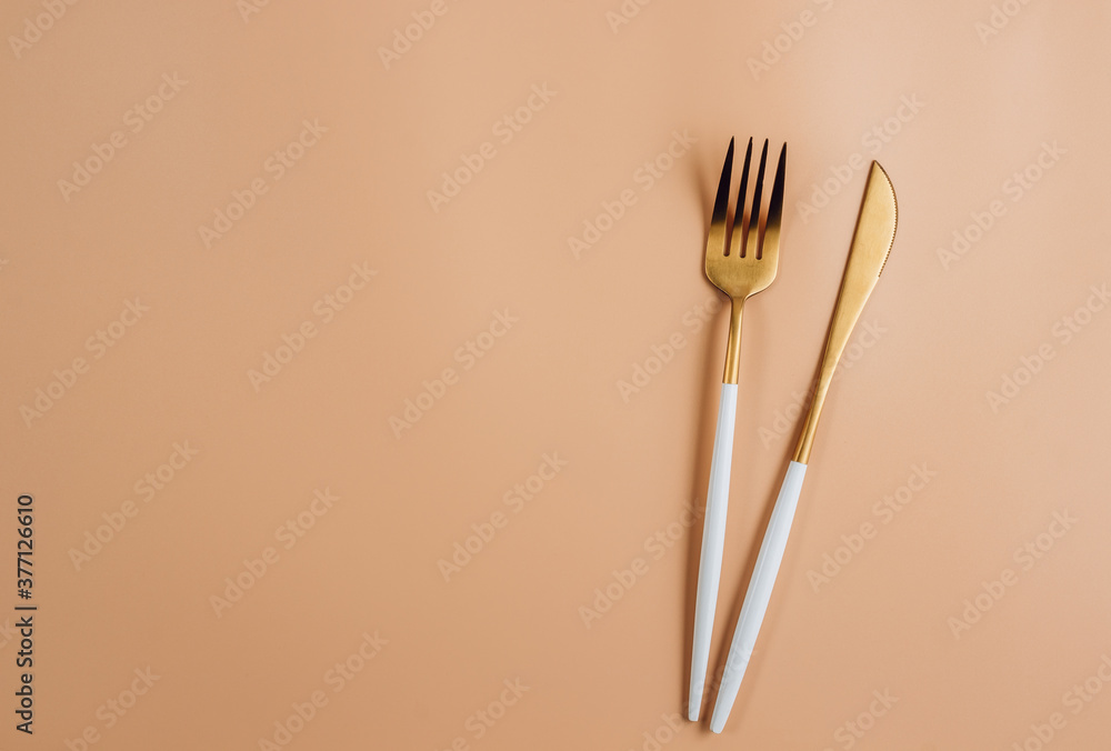 Festive table setting with golden cutlery on beige background Festive table setting with golden cutlery on beige background