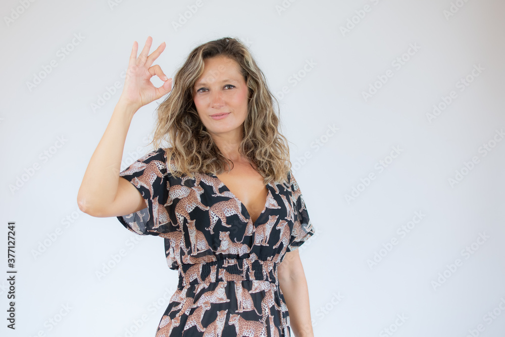 Beautiful woman in printed dress making the okay gesture Beautiful woman in printed dress making the okay gesture
