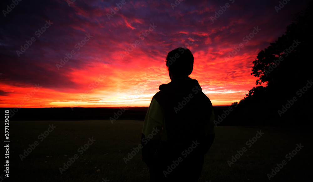 silhouette of young man with colorful sky clouds, sunset time, 