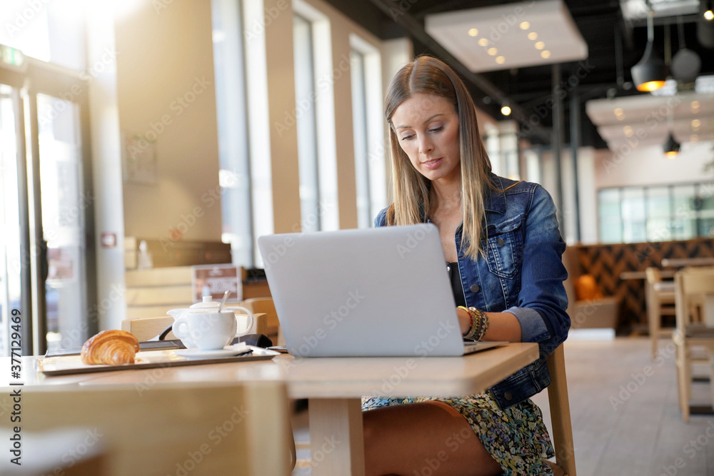 Young woman sitting at coffee shop and working on laptop Young woman sitting at coffee shop and working on laptop