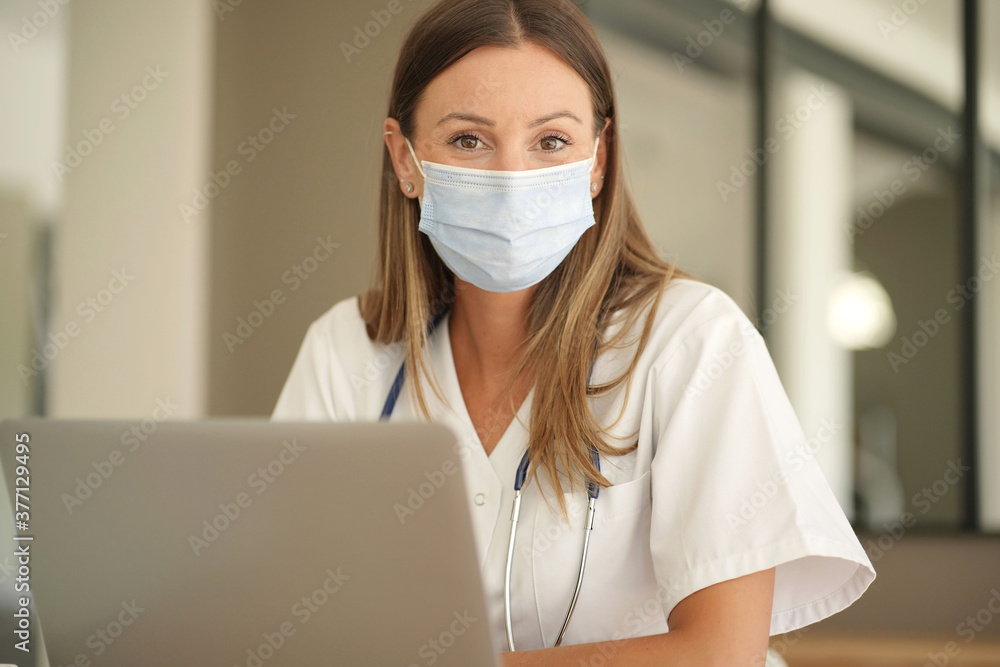 Portrait of nurse with face mask working on laptop in the office Portrait of nurse with face mask working on laptop in the office