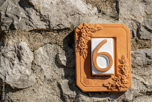 Close-up of house number 6 (six) on a stone wall in the small village of Tellaro. Liguria, Italy, Europe 