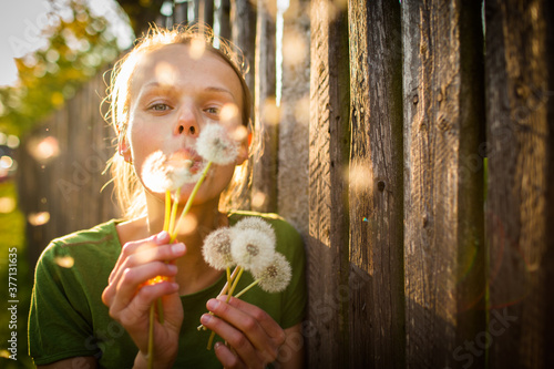 Portrait of happy young woman relaxing on a lovely summer day   playing with dandelions