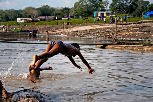 crianças nadando e brincando no rio solimões nas proximidades do porto . photo