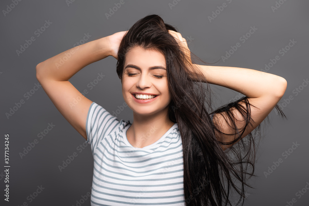 brunette woman with closed eyes smiling and touching hair isolated on black brunette woman with closed eyes smiling and touching hair isolated on black