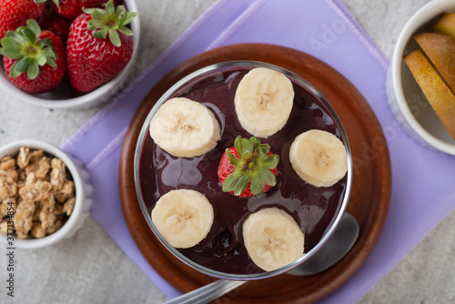 Brazilian typical acai bowl with fruits and muesli over wooden background. Top view