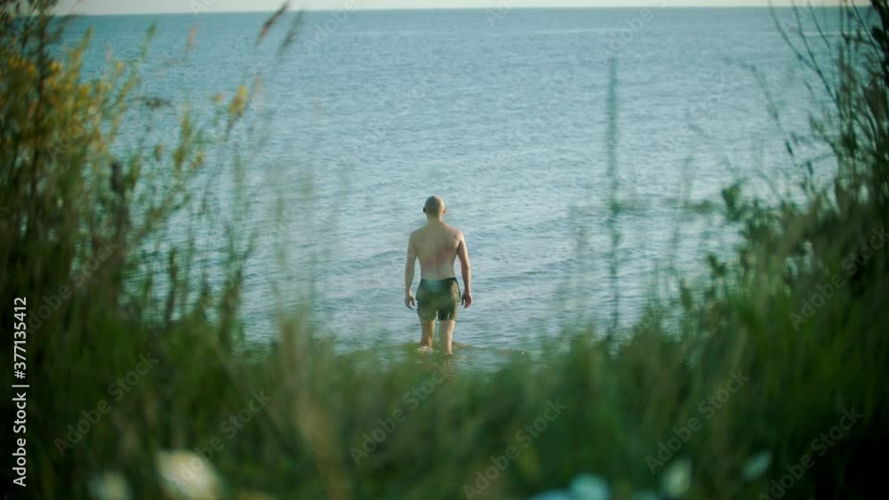 Young bald caucasian man walking in the river Young bald caucasian man walking in the river