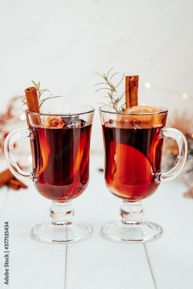 two glasses of hot mulled wine with rosemary on a white plate in a New Year's atmosphere two glasses of hot mulled wine with rosemary on a white plate in a New Year's atmosphere