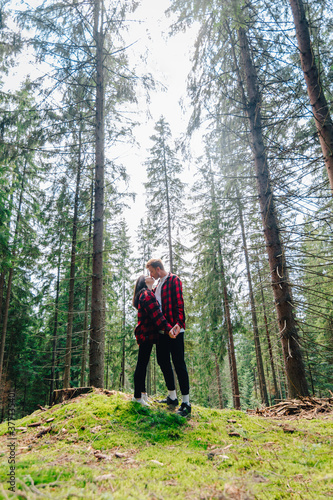 Young couple in love hugging and kissing in the woods. Young man and a girl kiss while walking in the untouched forest, standing on the moss and hugging. Lovestory