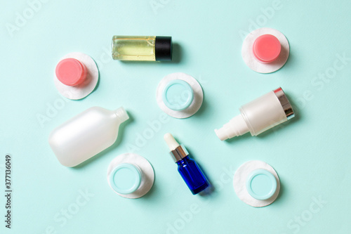 Group of small bottles for travelling on colored background. Copy space for your ideas. Flat lay composition of cosmetic products. Top view of cream containers with cotton pads