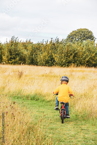 Young school age boy rides his bike across a path through a field