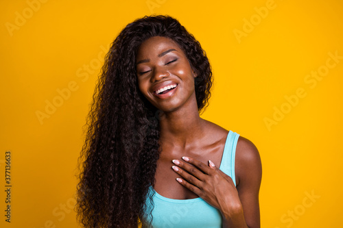 Photo portrait of young african american woman sighing in relief touching chest with hand isolated on vivid yellow colored background